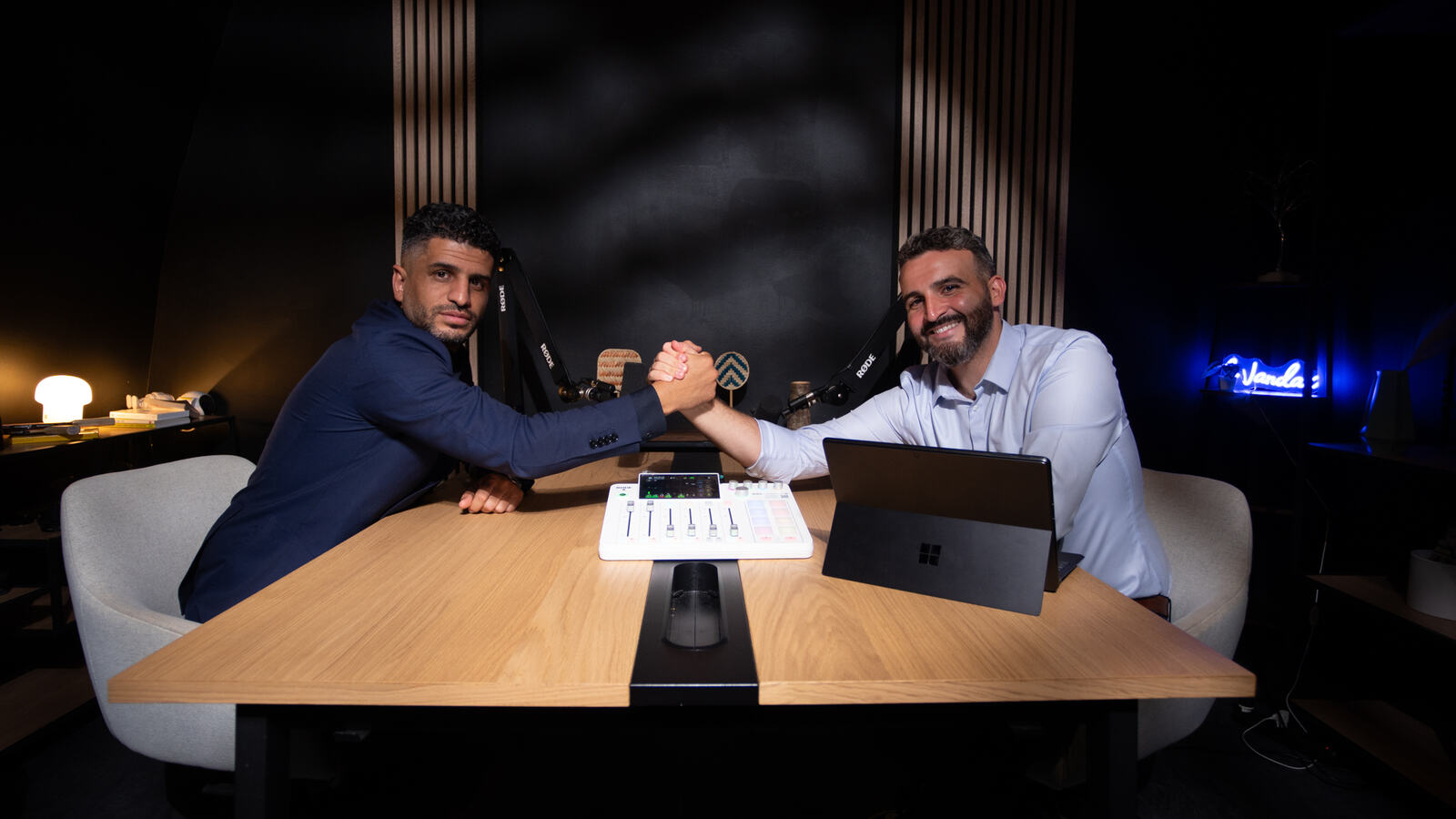 Deux invités face à face à la table du studio, micros et console entre eux